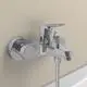 Chromene Badearmatur von Ideal Standard, montiert an einer Wand, mit einem Hebel und einem Ablaufschlauch, der zur Badewanne führt.